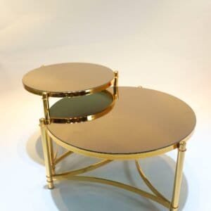 Two gold round nesting tables with mirrored tops and slender interconnected legs.