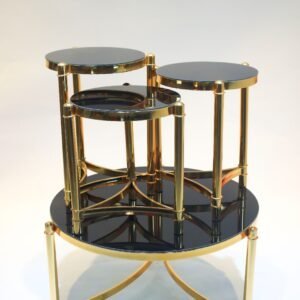 Nested tables with round black glass tops and gold metal frames, arranged in stacked form.