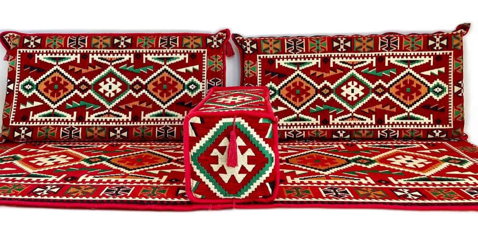 Traditional woven cushions and mat with intricate red, green, white geometric patterns.