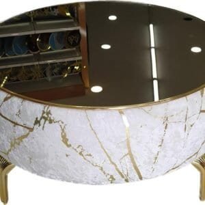 Round coffee table with black top, white and gold marbled base, four gold legs.