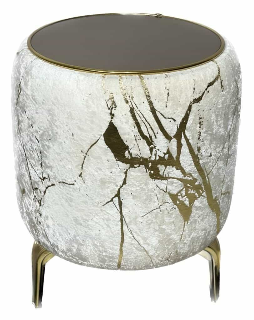 Cylindrical Side Table With Textured White Surface, Gold Veins, Dark Top, And Gold Legs.